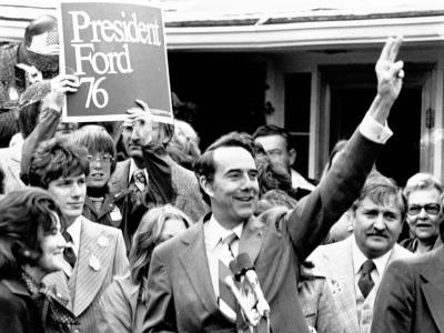 Bob Dole Waving to Crowd Outside House in Russell, KS with Ford/Dole '76 Campaign Sign | Robert and Elizabeth Dole Archive and Special Collections