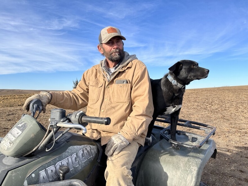 Russell County rancher Rich Koester sits on his four-wheeler with his dog Gibbs. David Condos / Kansas News Service